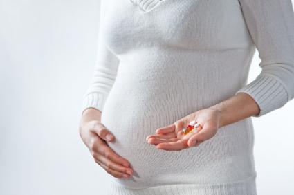 A pregnant woman with medications in her hand.