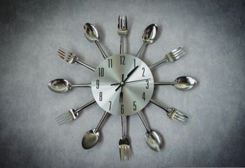 Clock surrounded by utensils.