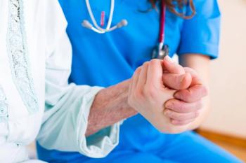 A nurse holding an elderly patient's hand.