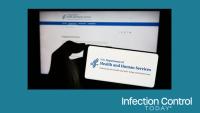 Person holding a mobile phone with the logo of the US Department of Health and Human Services (HHS) in front of a web page. (Adobe Stock 672110075 by Timon)