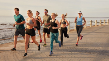 a group of people running on the boardwalk by the ocean