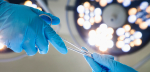 Gloved hands handing off a surgical tool.  (Adobe Stock, 55841465 by Xixinxing)