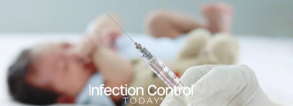A doctor's hand wearing a medical glove holds a syringe against a blurred background of a small, crying newborn infant lying down during vaccination. (Adobe Stock 476226620 by Stella)