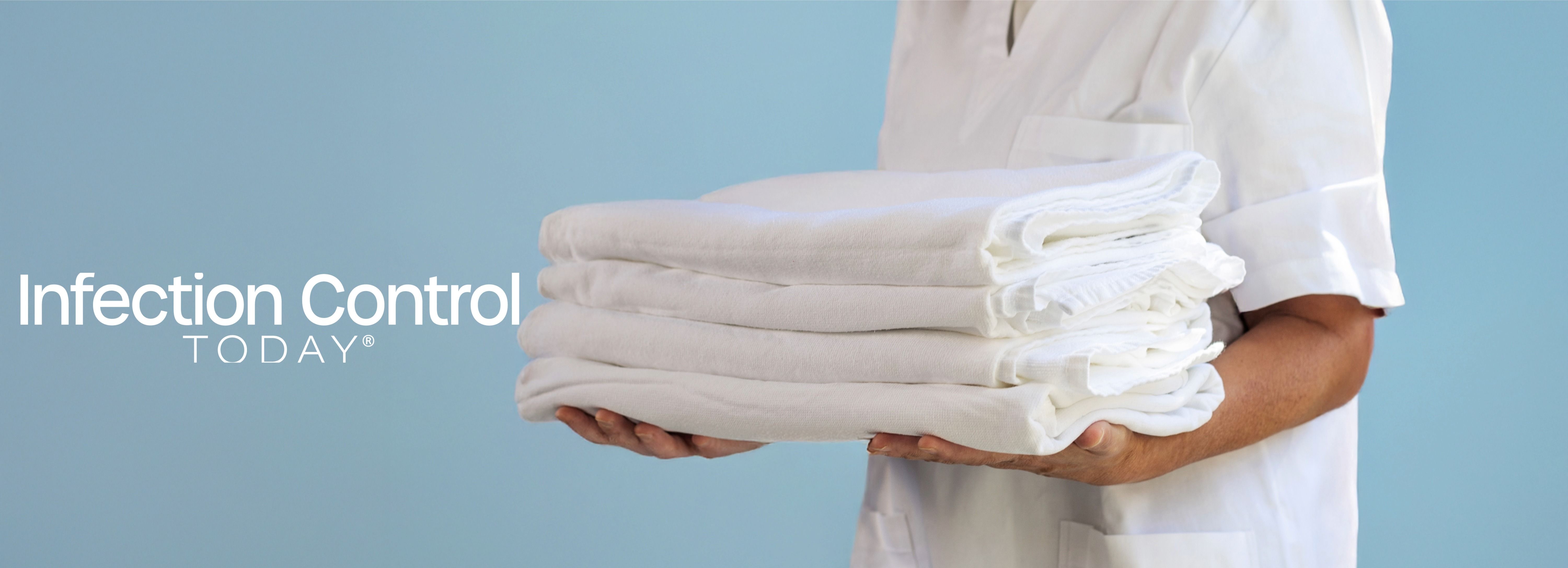 A health care professional presents a stack of pristine white textiles. (Adobe Stock 1506900633 Travel Studio Stock) 
