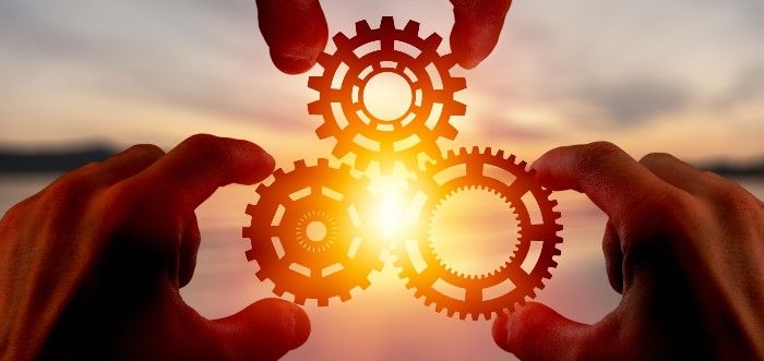 Collaboration.  Three hands holding wheels whose cogs intermingle