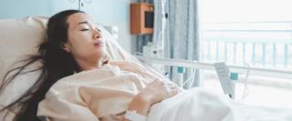 woman lying ill in hospital bed