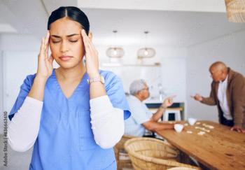 Woman in scrubs holding temples ©Sharne/peopleimages.com-stock.adobe.com