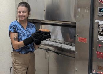 Maria Rottersman of UC Davis holds a loaf of baked bread made using seed varieties developed without alpha-gliadin proteins, a component of gluten. © Alejandra Andrade / California Wheat Commission