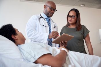 Doctor at patient bedside talking to family member ©Gregory Miller - stock.adobe.com