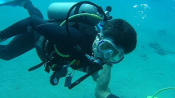 Dr. Tony Mok scuba dives with a dolphin.