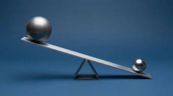 teeter totter on blue background with silver balls on either end  image credit: ©Munmun stock.adobe.com