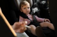 child in car seat with the hand of a person smoking in the foreground | ©New Africa stock.adobe.com