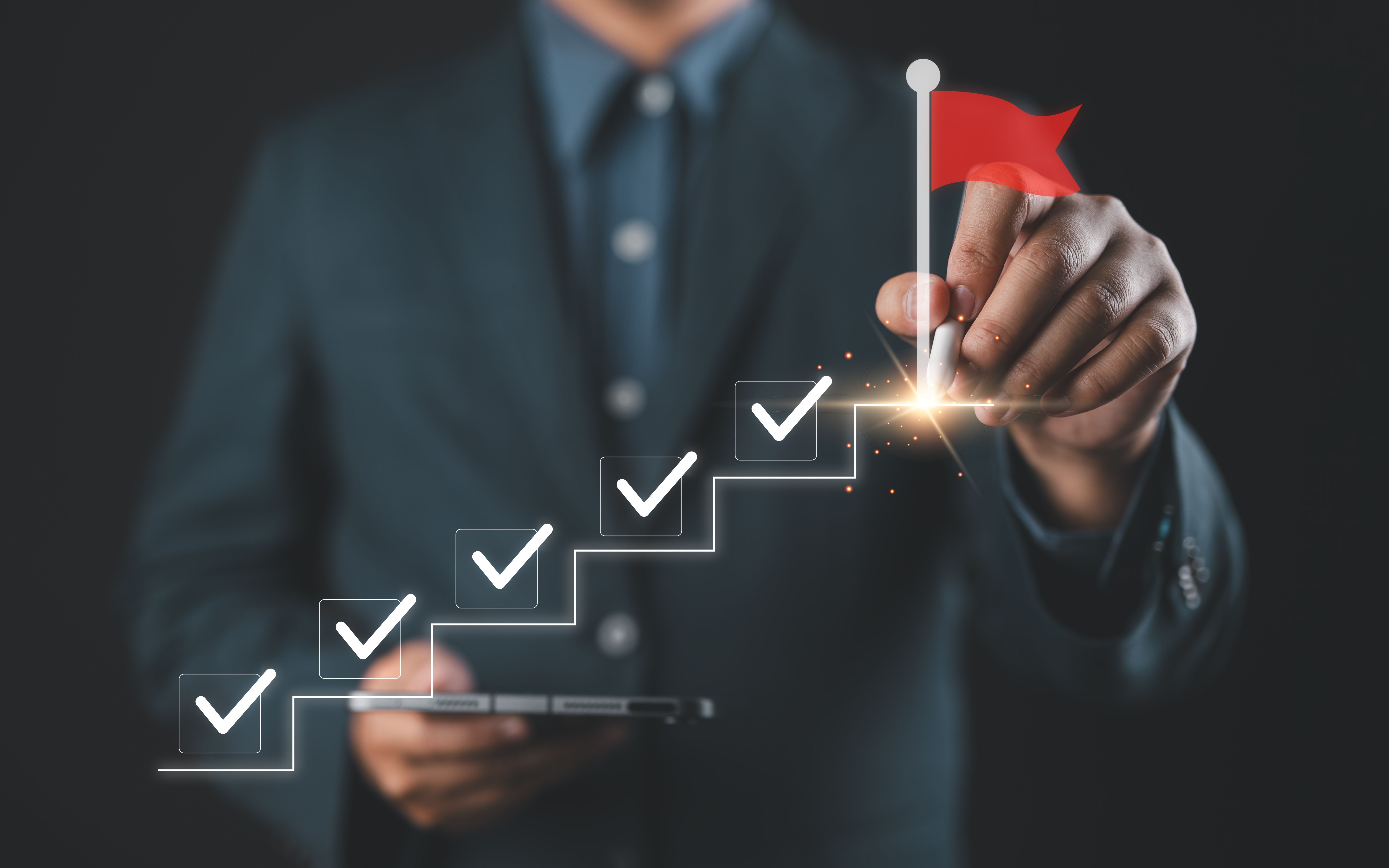 Businessman drawing checkmarks on virtual staircase steps toward achieving goals | image credit" ©Nirusmee stock.adobe.com
