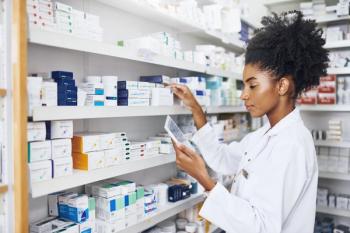 pharmacist checking tablet with shelves filled with drugs| image credit ©JordaanExam/peopleimages.com stock.adobe.com
