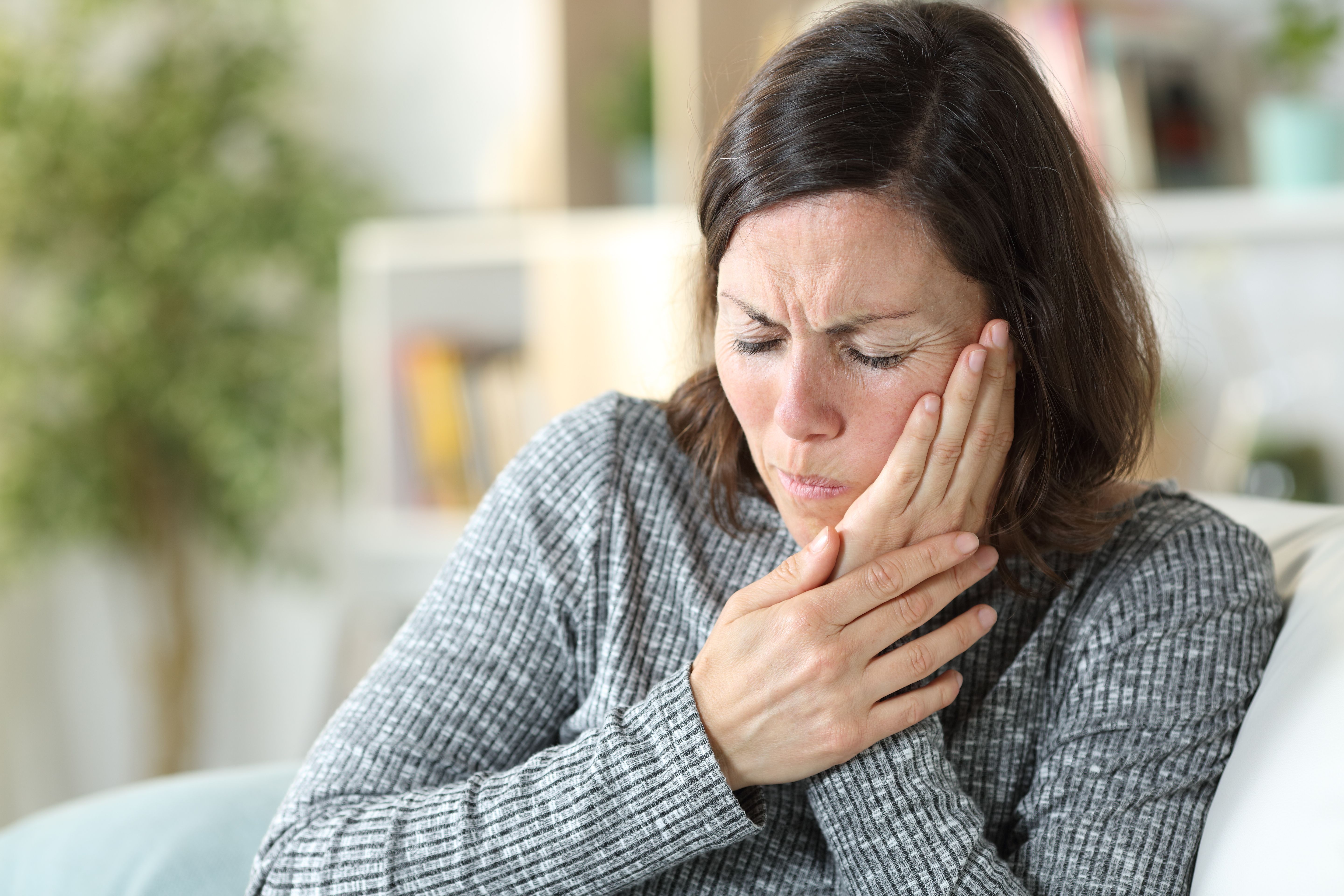 woman holding side of face with painful grimace | Image credit: ©Pheelingsmedia stock.adobe.com