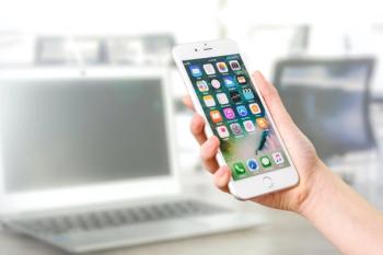 picture of a person holding a smartphone with home screen apps visible