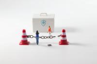 illustration of barriers to access, chain between two traffic cones with minature doll of a person | ©maria pilar martinez stock.adobe.com
