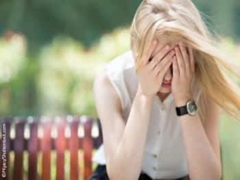 Woman sitting with face in hands headache pain migraine