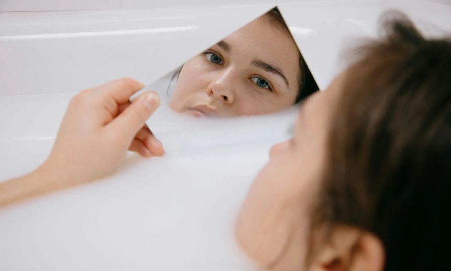 woman in bath looking in a mirror