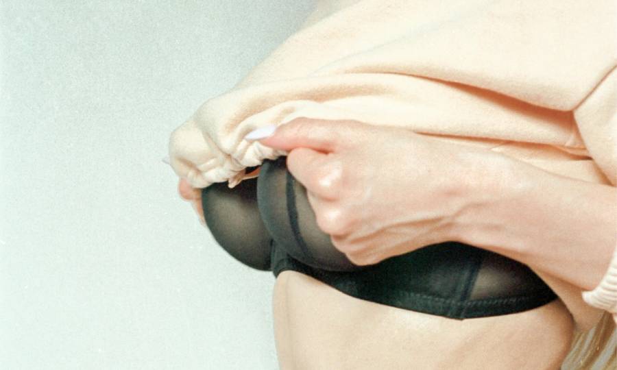 woman lifting her shirt to reveal a black bra
