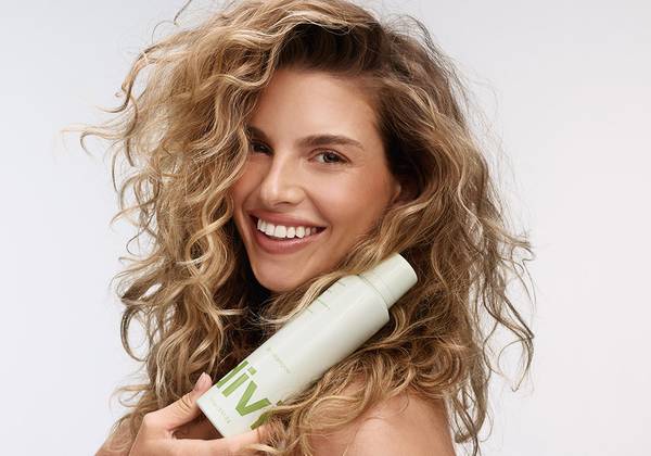 Model with wavy hair posing with Divi Lift+Refresh Dry Shampoo
