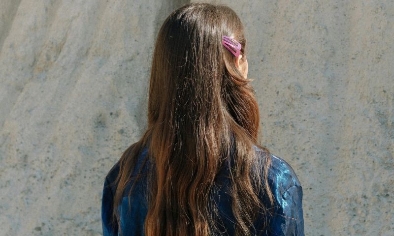 A woman with long brown hair standing in front of a rock formation