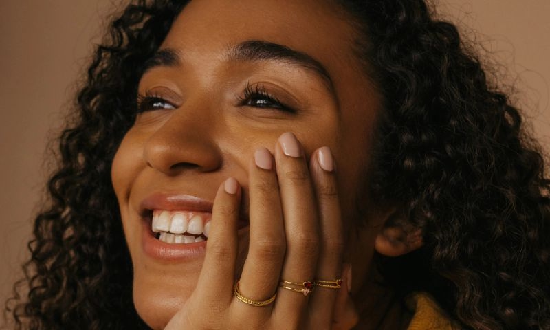 woman smiling with hand on cheer