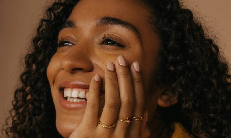 woman smiling with hand on cheer