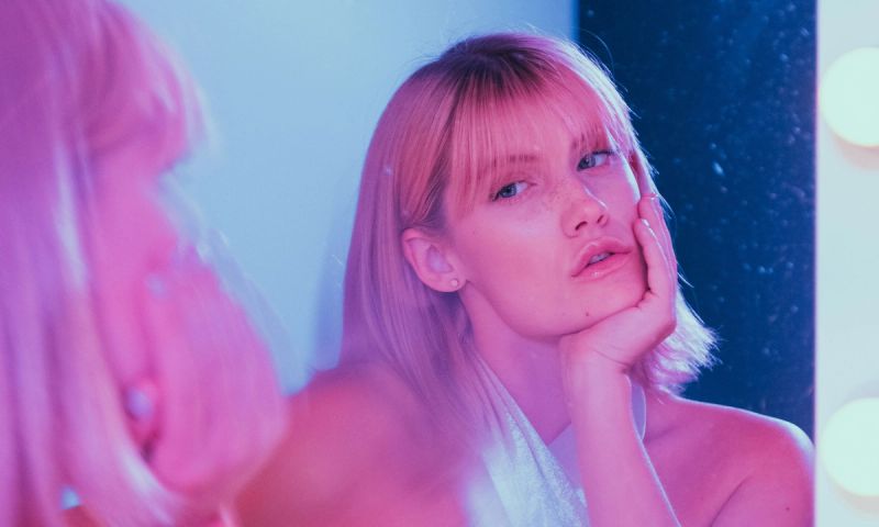 blonde model looking into mirror in pink and blue tinted image