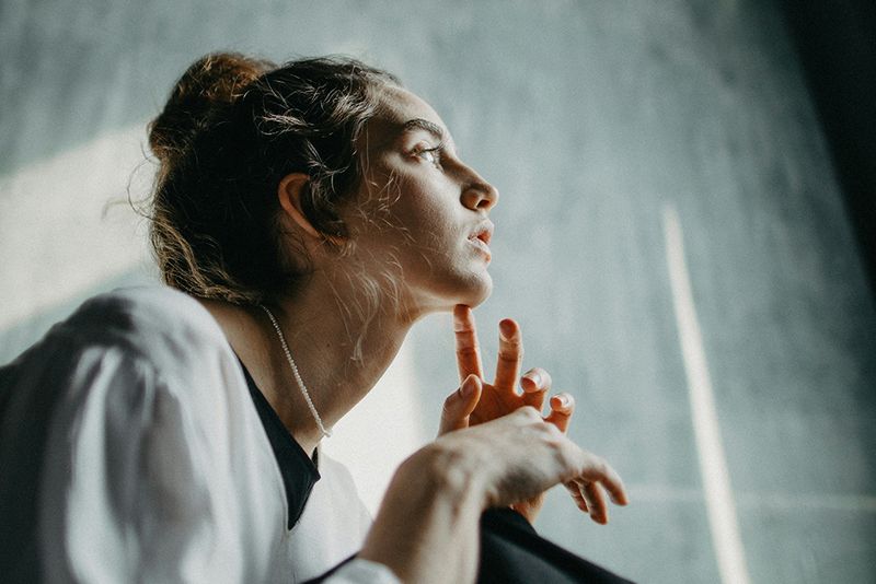 woman looking away with hands on chin