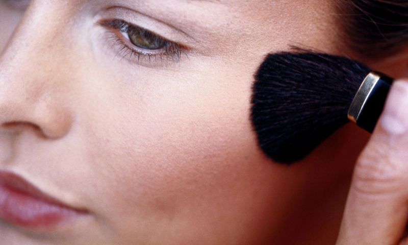 Woman applying blush to cheek