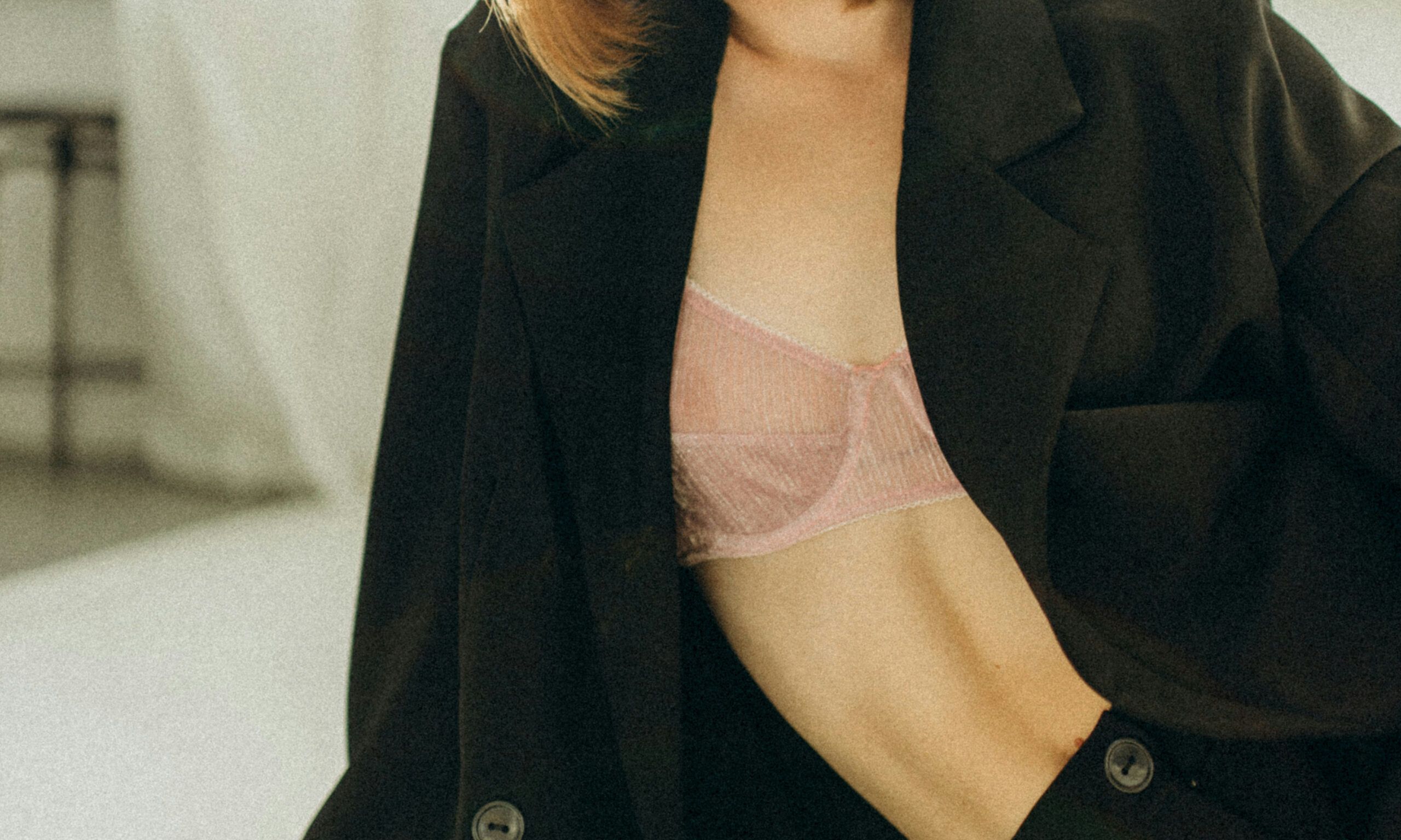 close up of woman in black blazer and pink bra