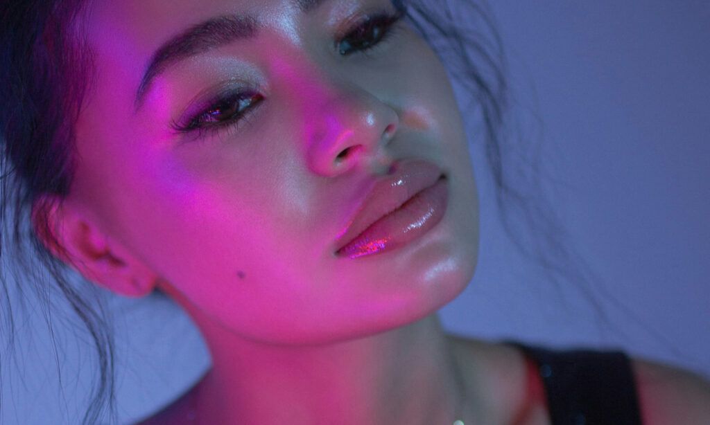 woman with glossy lips in blue and purple lighting