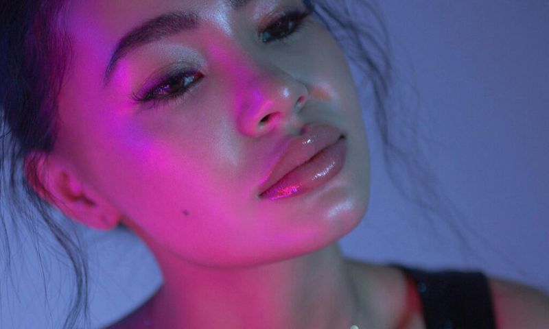 woman with glossy lips in blue and purple lighting