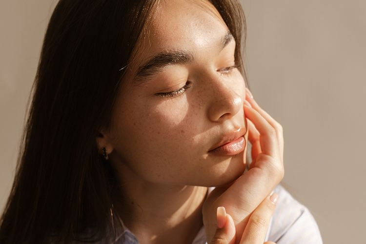 young woman with hand on chin looking to the side