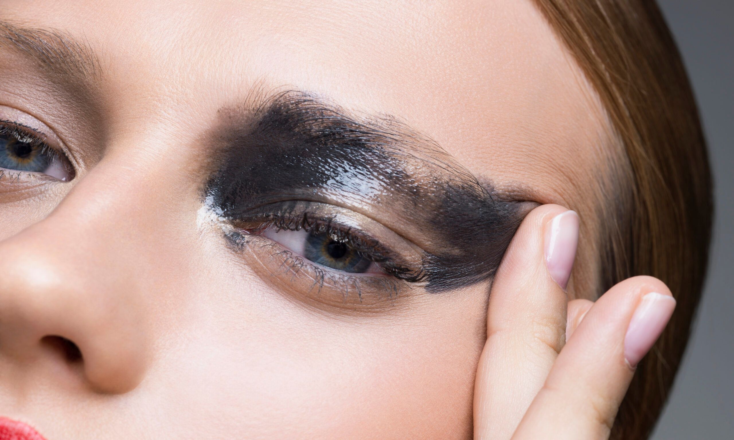 Portrait of young woman smudging mascara with finger, studio shot