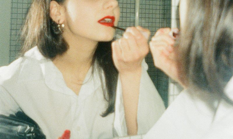 mirror shot of woman putting on red lipstick