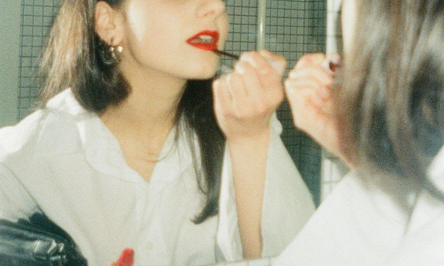 mirror shot of woman putting on red lipstick