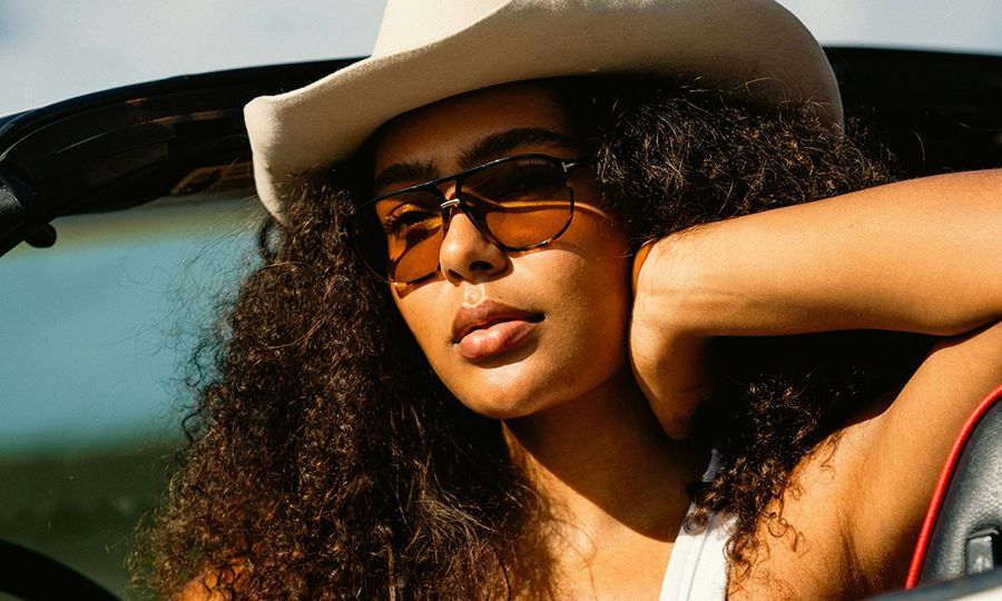 woman sitting in convertible car with hat and sunglasses