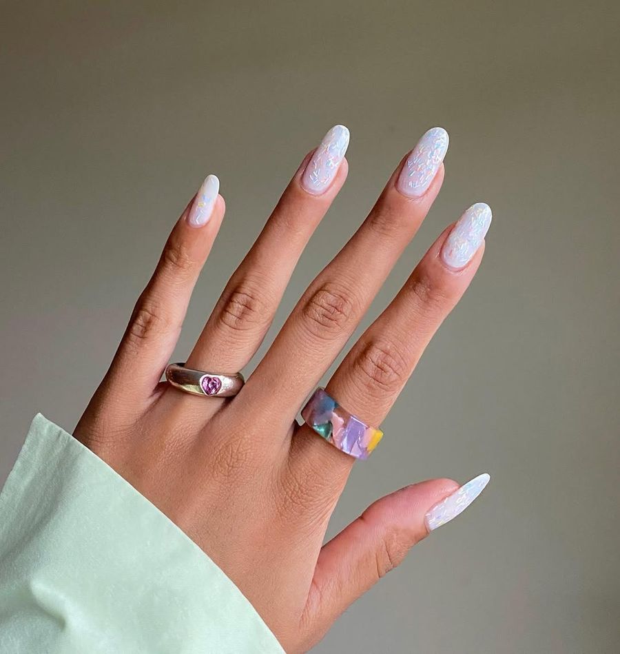 Long round nails with a sheer, glitter polish.