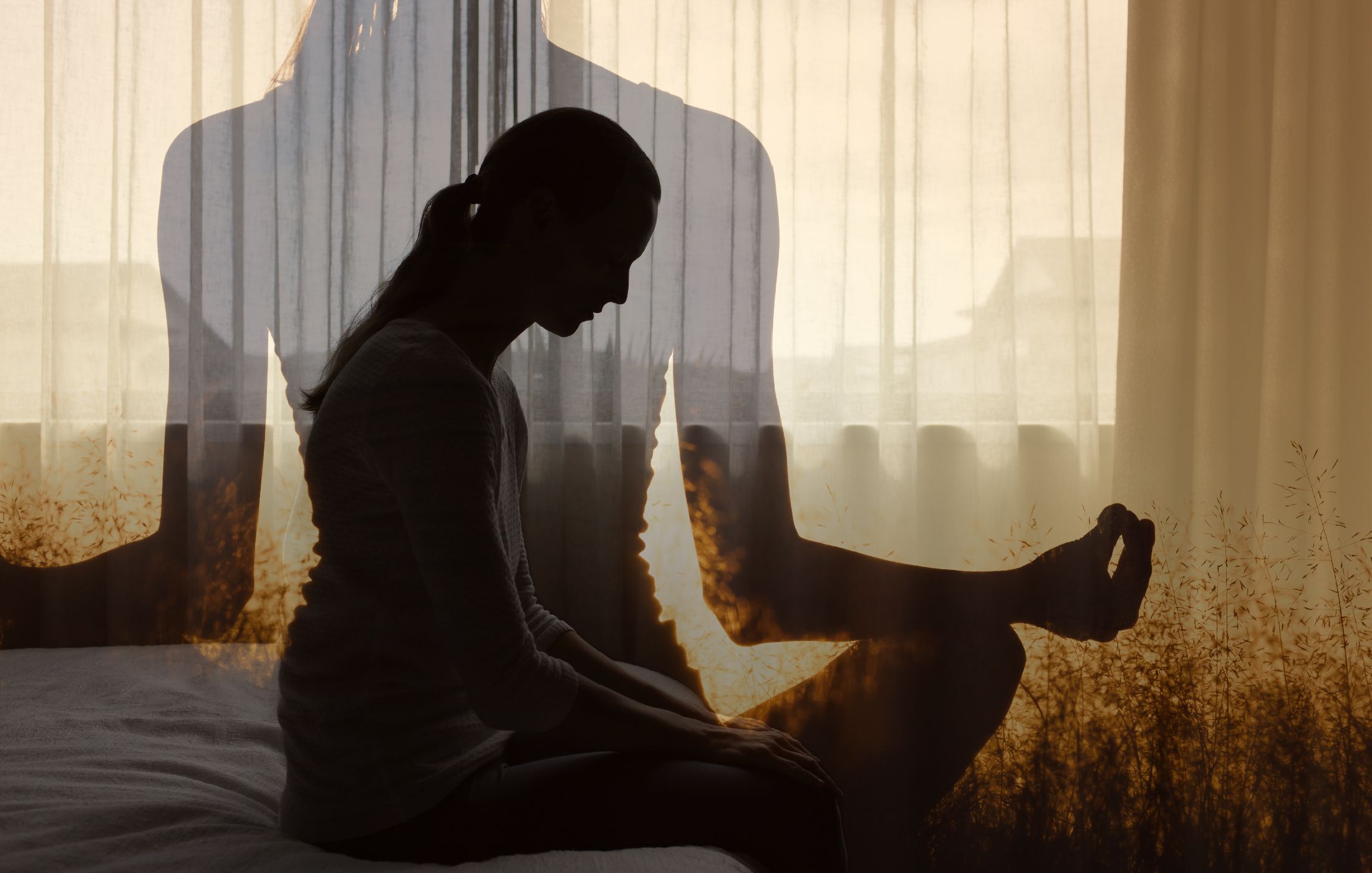A silhouetted woman sits on a bed in front of a sunlit window, layered with a meditative figure in a double-exposure effect.