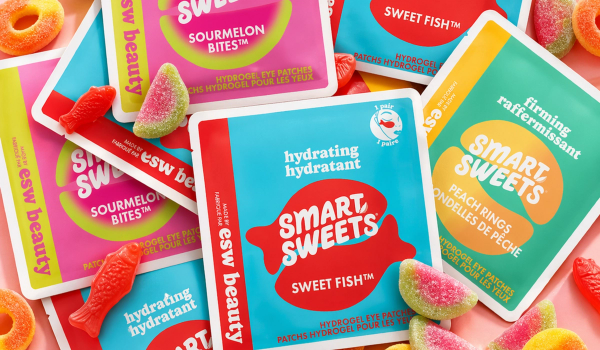 Colorful SmartSweets x ESW Beauty hydrogel eye patch packets in Sweet Fish, Sourmelon Bites, and Peach Rings flavors, surrounded by matching gummy candy.