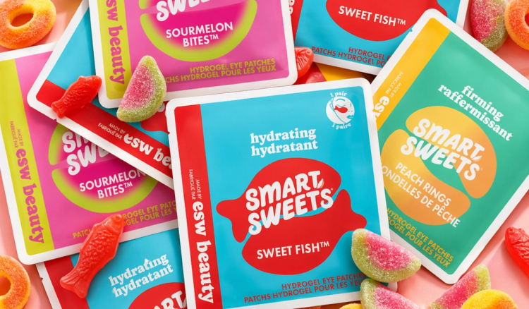 Colorful SmartSweets x ESW Beauty hydrogel eye patch packets in Sweet Fish, Sourmelon Bites, and Peach Rings flavors, surrounded by matching gummy candy.