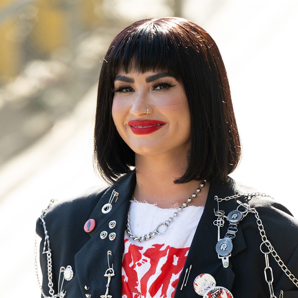 Demi Lovato with dark blunt bob and bangs wearing red lipstick and a leather jacket