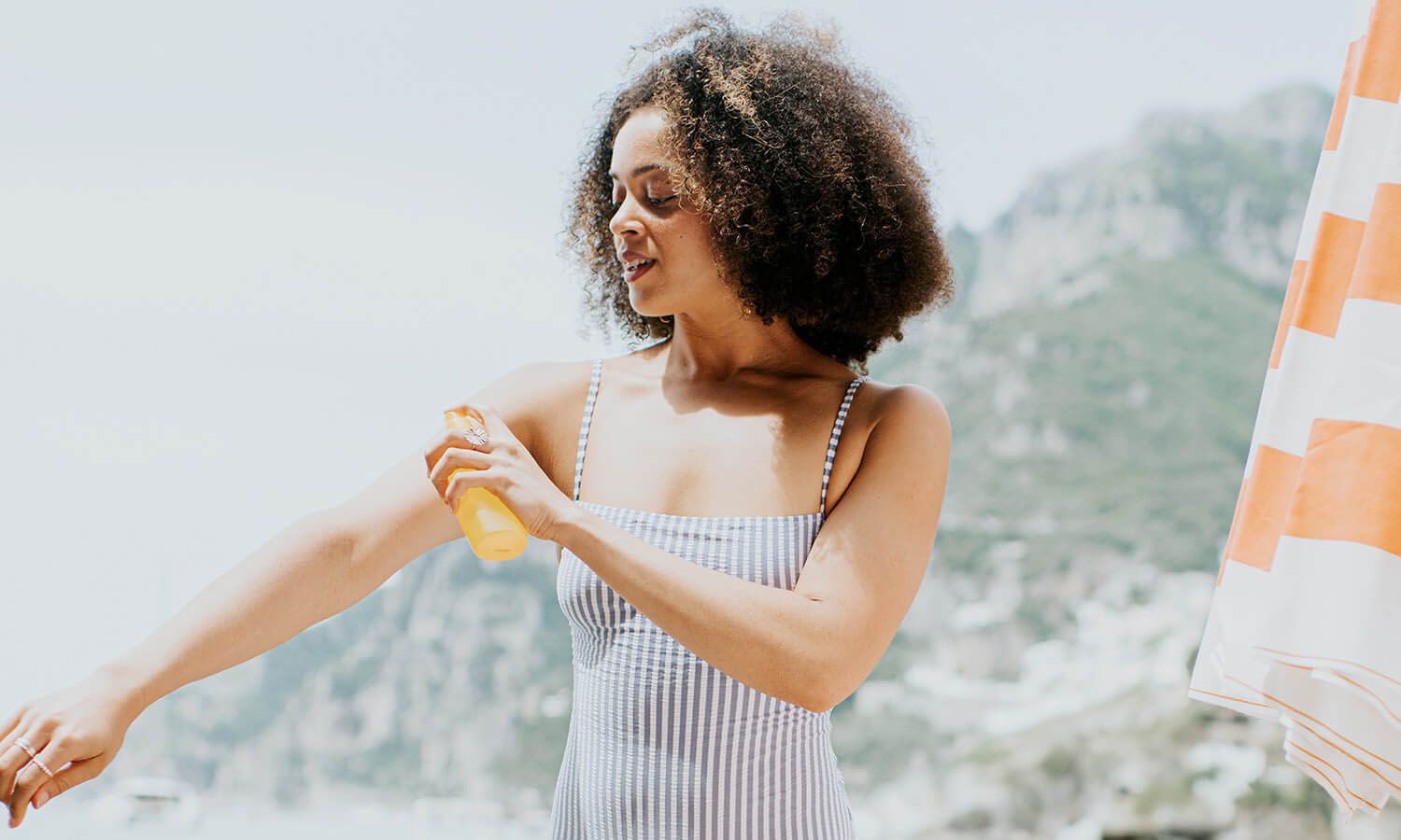 Woman at the beach applying sunscreen on her arm