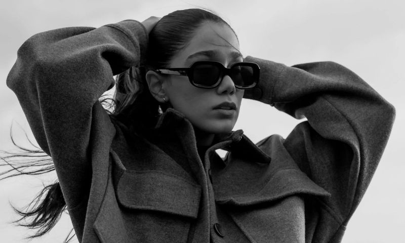 black and white image of woman wearing a jacket putting her hair up