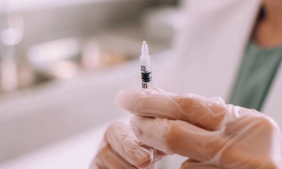 Gloved hands holding a syringe