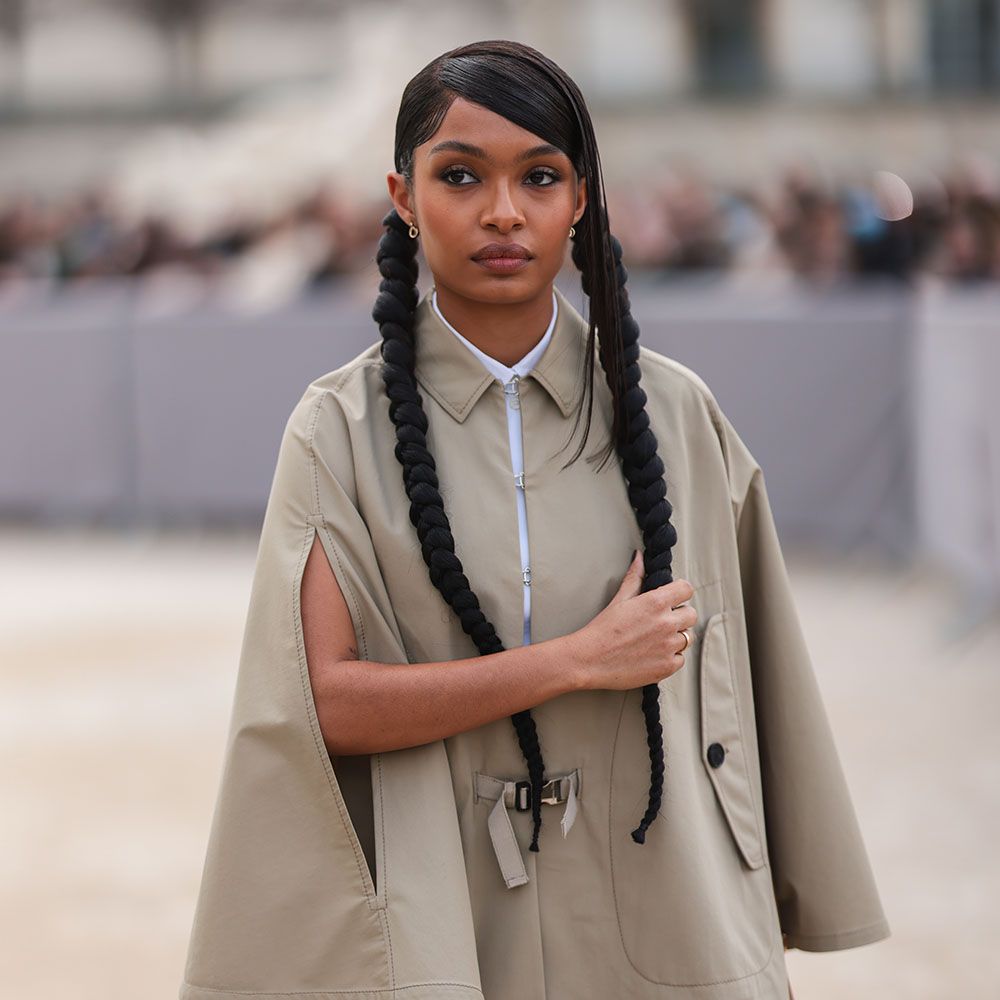 Yara Shahidi walking with long braided pigtails wearing a trench coat cape