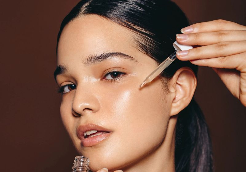 woman placing serum on face with dropper