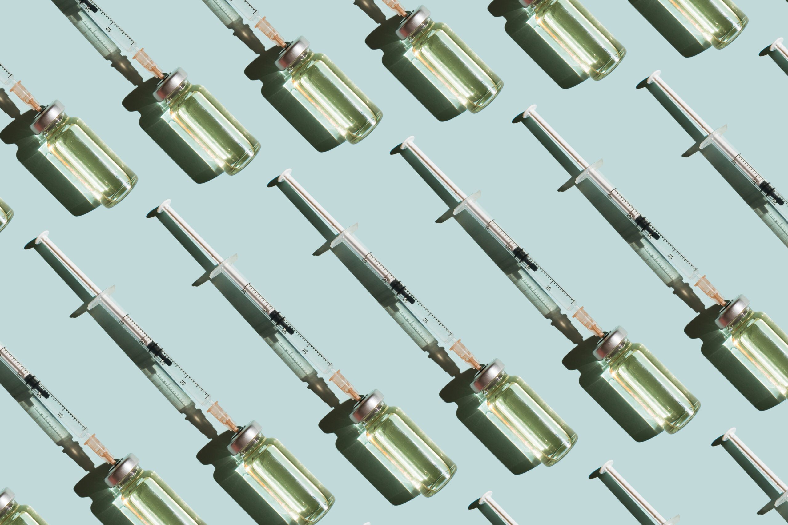 Pattern of vials and syringes with a vaccine on a blue background. Concept of medical treatment or vaccination.